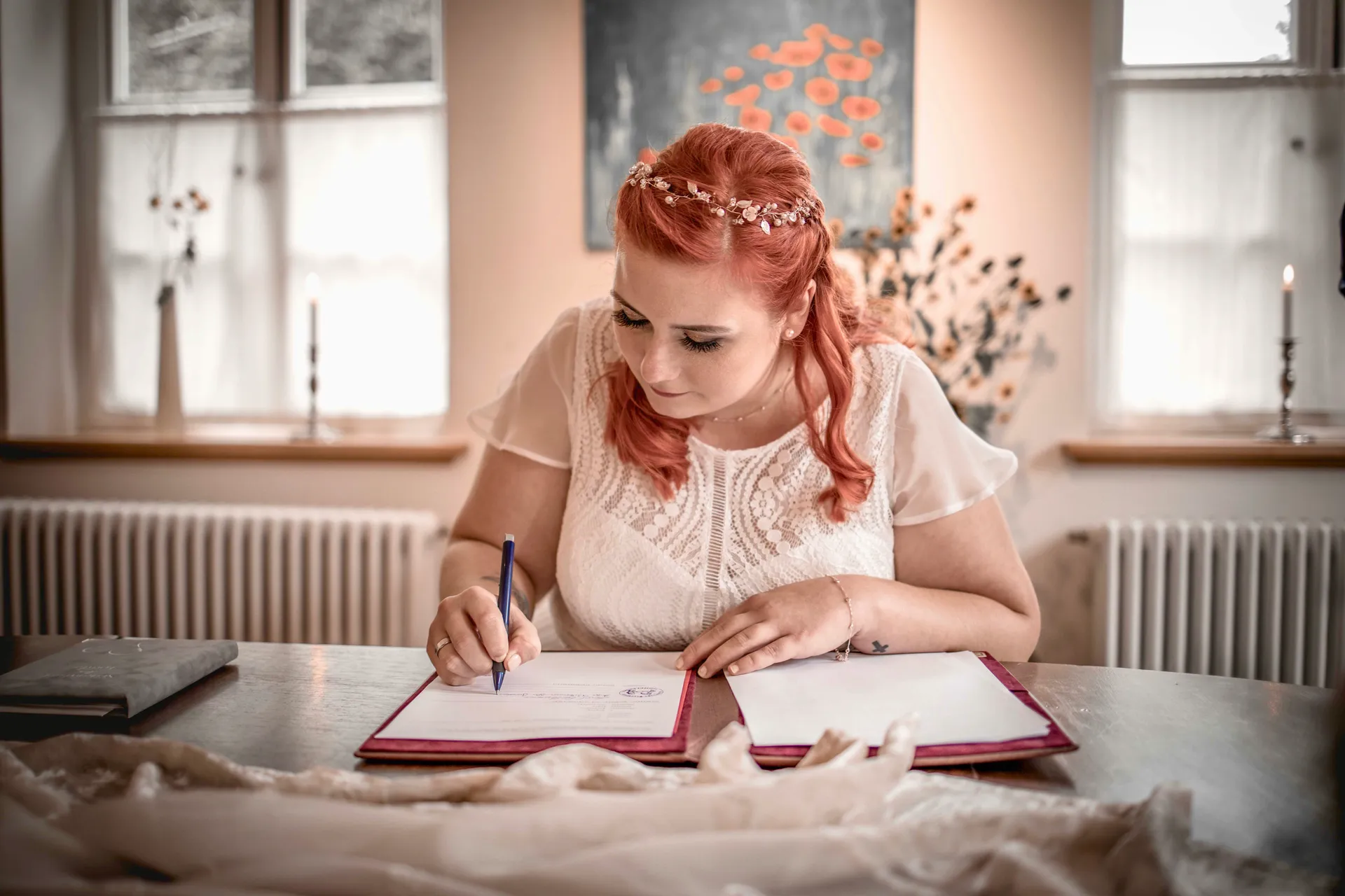 Braut mit Blumenkranz im roten Haar unterschreibt die Trauungsurkunde im Standesamt